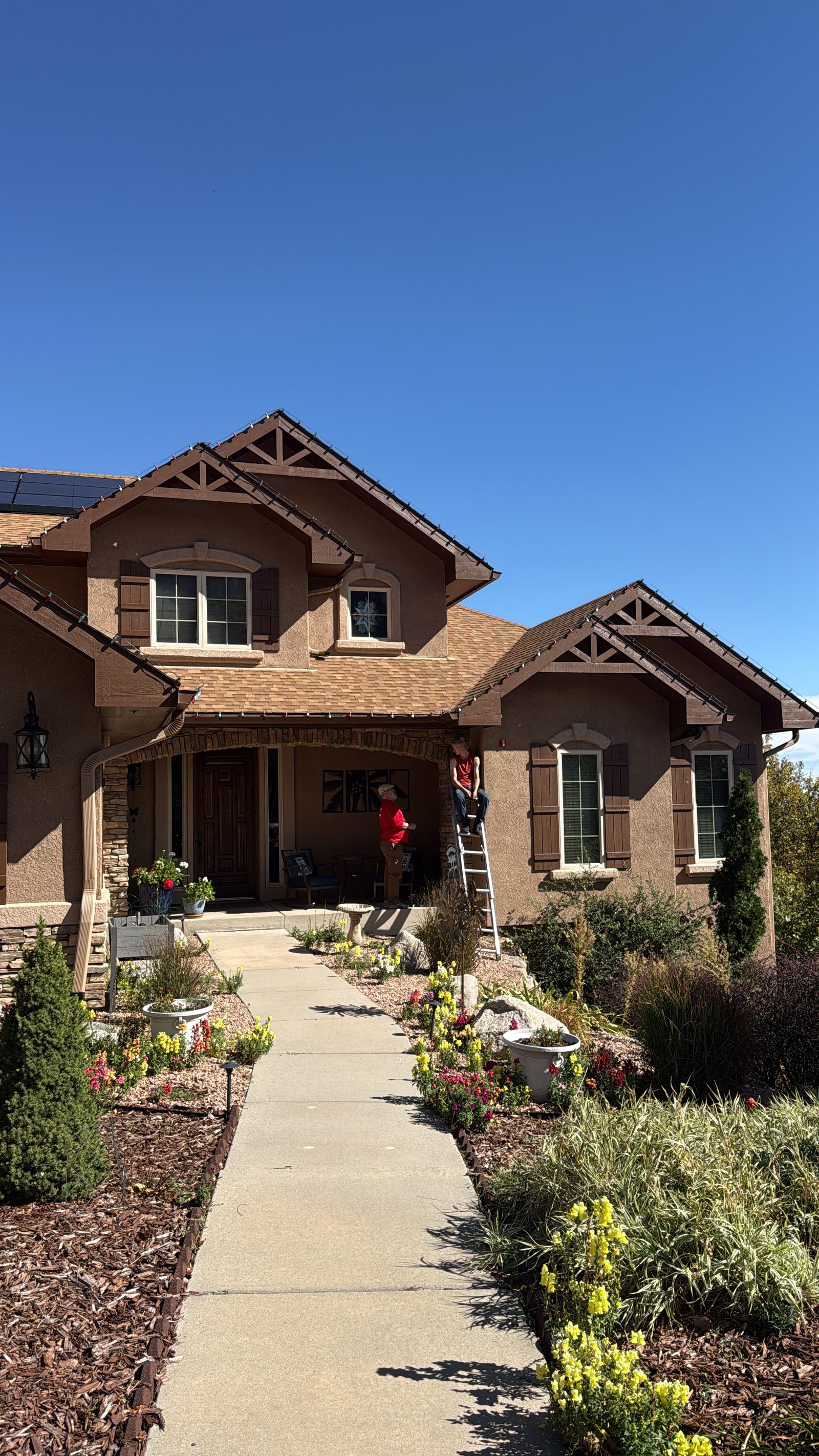 Colorado Front Range Christmas light installation in progress on a tan stucco two-story residential home