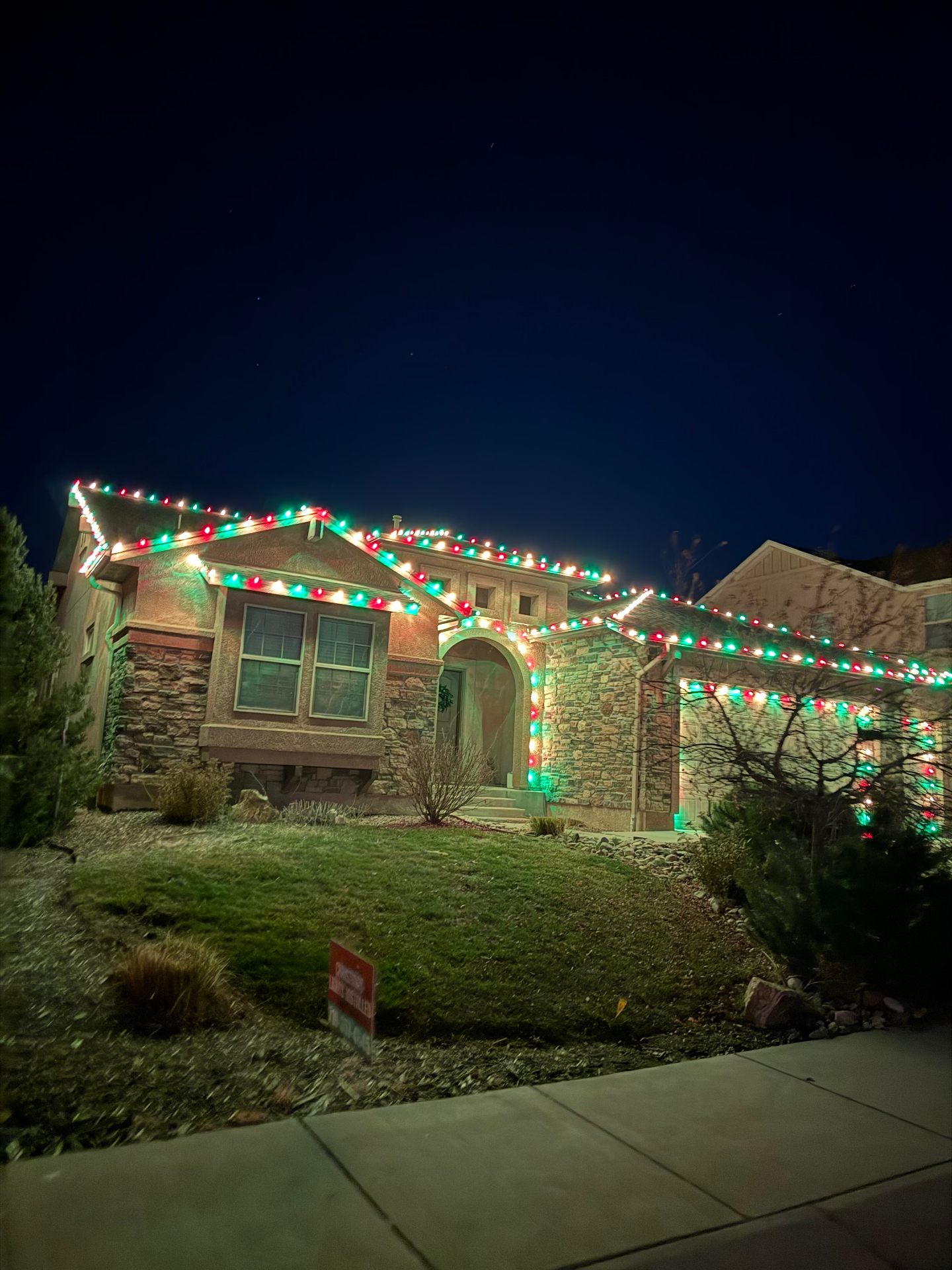 Multicolor Christmas lights on a two-story Colorado Front Range home with roofline and landscape holiday lighting