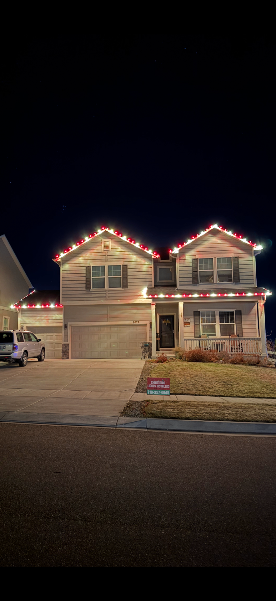 Red and white Christmas light installation on a two-story Colorado Front Range home's roofline and garage